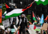 Protesters with flags and signs, one holding a megaphone.