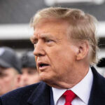Trump RAGES At Reporter After Touchy Question Man in suit and red tie speaking outside.