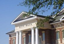 Shocking Scandal: Mayor’s Secret Ties to China Exposed Exterior view of a city hall building with columns and a clear blue sky