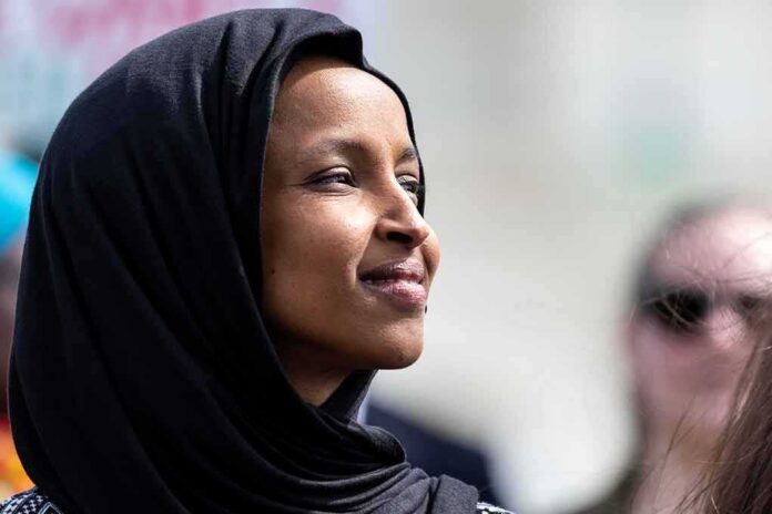 Woman wearing a black hijab looking thoughtfully during an outdoor event
