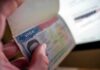Parliament Abolishes Permanent Residence For Migrants! A hand holding an open passport displaying a visa page