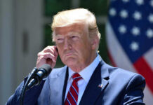 Federal Court Defies SCOTUS, Rules Trump Can’t Fire DEI Officers Man in a suit adjusting an earpiece.