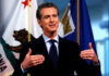FBI Informant REVEALED – Infiltrated Newsom’s Circle Man speaking with flags in the background