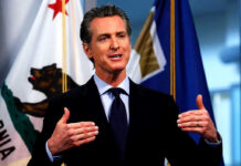 FBI Informant REVEALED – Infiltrated Newsom’s Circle Man speaking with flags in the background