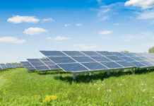 Big Tech Now GRABBING Native American Land! Solar panels in a grassy field under blue sky.