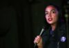 woman speaking into a microphone on a dimly lit stage