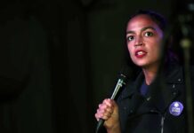 AOC Voice Flip Sparks Fury woman speaking into a microphone on a dimly lit stage