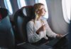 Passenger with headphones seated by airplane window