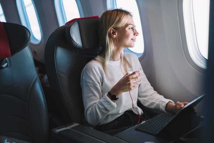 shutterstock_1321399355 Passenger with headphones seated by airplane window