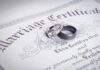Two wedding rings resting on a marriage certificate
