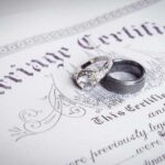 Two wedding rings resting on a marriage certificate