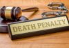 Gavel, handcuffs, and a nameplate reading death penalty on a wooden desk