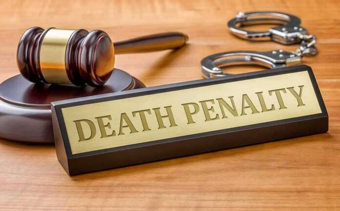 Gavel, handcuffs, and a nameplate reading death penalty on a wooden desk