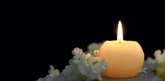 Candle on an open book with white flowers