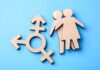 Wooden transgender symbol and two human figures on blue background