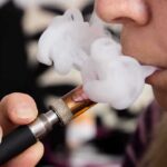 Urgent Warning For Anyone Vaping While on GLP1’s Close-up of a person vaping, exhaling smoke clouds
