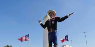 Giant cowboy statue towers over a crowd at an outdoor event