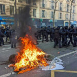 Belfast Erupts: Police UNLEASH Water Cannons! Fire burning on the street amid police presence.