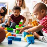 Mamdani Launches Babysitting Services To Residents Karyn Polito with toddlers building blocks on a play mat