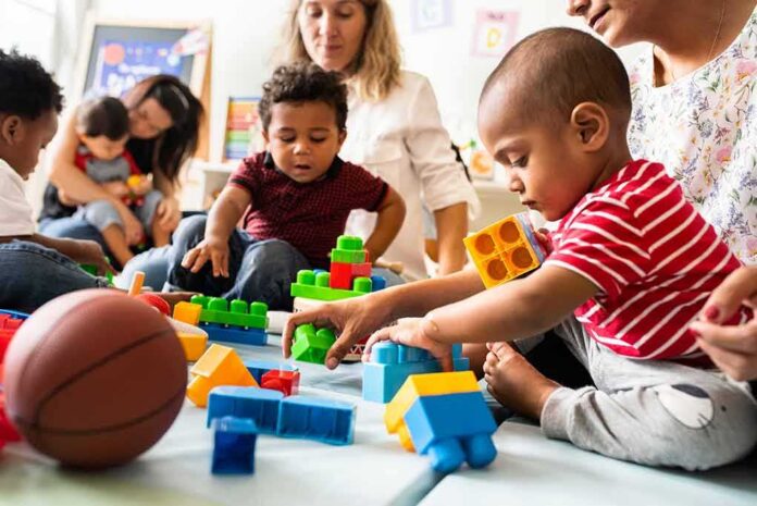 shutterstock_1247691913 Karyn Polito with toddlers building blocks on a play mat