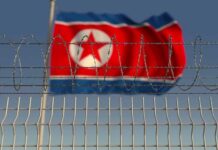 N.Korean Prisoners Captured During Ukraine War Barbed wire fence with North Korean flag in background