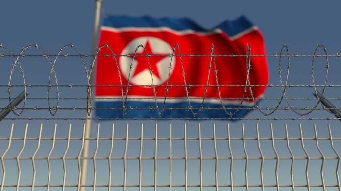 shutterstock_1336464401 Barbed wire fence with North Korean flag in background