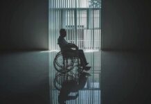 Person in a wheelchair silhouetted by a large window