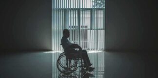 Person in a wheelchair silhouetted by a large window