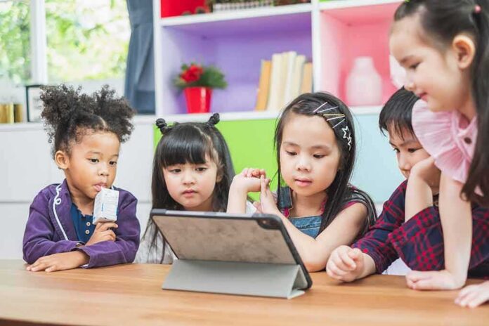 shutterstock_1407865199 children gathered around a tablet at a table