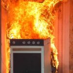 Kitchen stove engulfed in flames against a wall