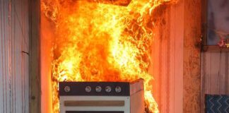Kitchen stove engulfed in flames against a wall
