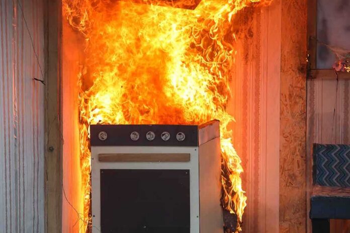 Kitchen stove engulfed in flames against a wall