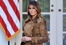 Melania Scores LUCRATIVE White House Side Hustle Melania Trump standing in a brown suede coat near an American flag