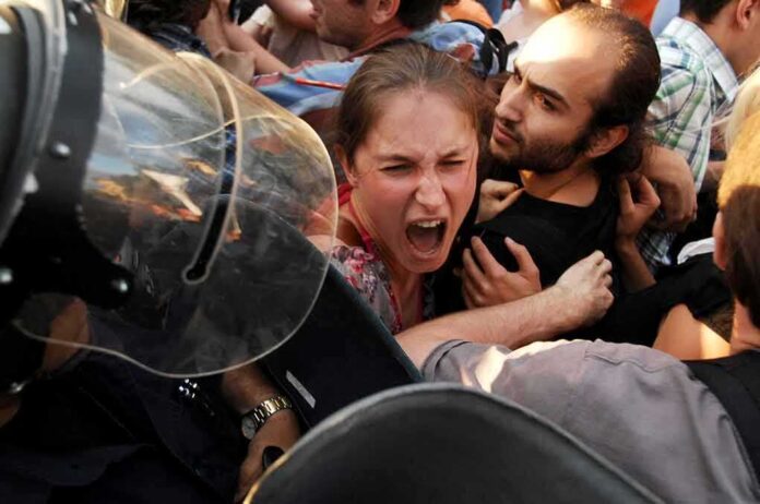 Protesters clash with riot police as woman shouts