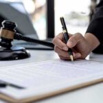 44 Members of Congress SPYED On — GOP DEMAND Prosecutions Hand signing legal document beside gavel and laptop