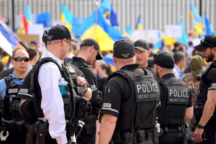 shutterstock_2132863557 Police officers stand among a crowd with blue and yellow flags