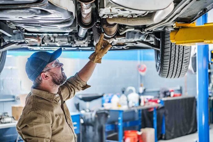 Mechanic inspecting underside of a car on a lift