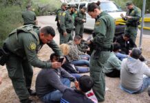 ICE Wrongly Deports Man TWICE in 6 Months Law enforcement officers process a seated group outdoors