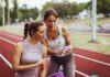 Trans Athletes Take 2,293 Championships From Biological Women Two women at a running track looking at a tablet