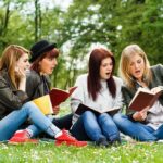 Visa End Slams STEM Industry Group of young women reading books on grass in a park