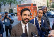 Zohran Mamdani speaking to reporters on a city sidewalk