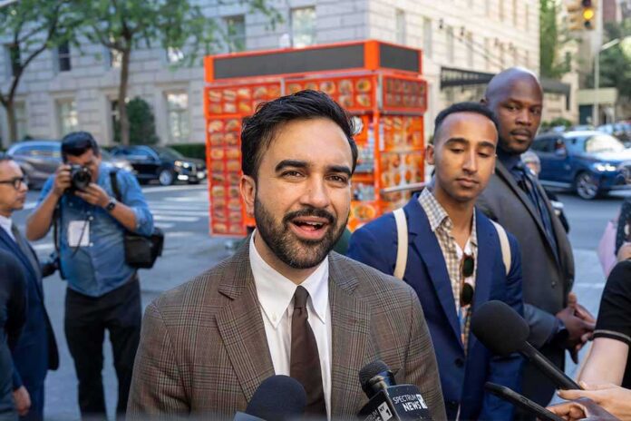 Zohran Mamdani speaking to reporters on a city sidewalk