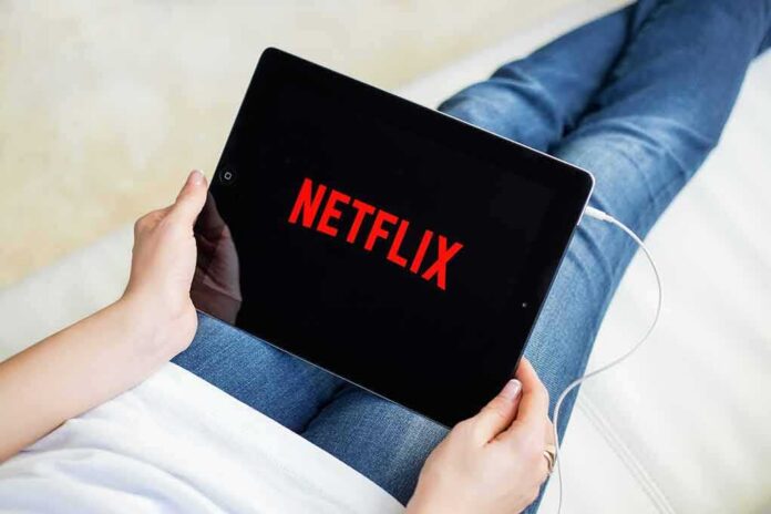 Person holding a tablet with streaming app on screen