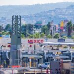 Consumer Panic: Avocado Pipeline Suddenly Freezes Border crossing booths at Mexico entry point with cityscape in background