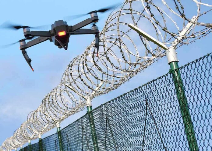 shutterstock_790134829 Drone flying near barbed wire security fence