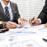 USA DROPS Billionaire’s $265M Bribery Scandal Two businesspeople in suits reviewing charts at a desk with a gavel