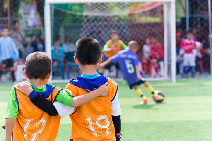 Two boys watching a soccer game together.