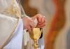 University Shock: Catholic Conversions Explode Priest holding a communion wafer over a gold chalice
