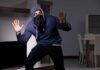 Thief Makes Embarrassing Blunder During Home Burglary Person in hoodie and face covering raising hands indoors