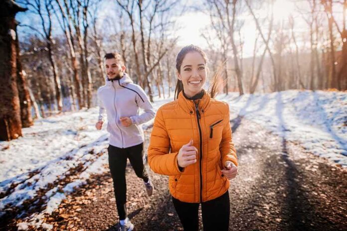 shutterstock_1196192464 Two people jogging on a snowy park path